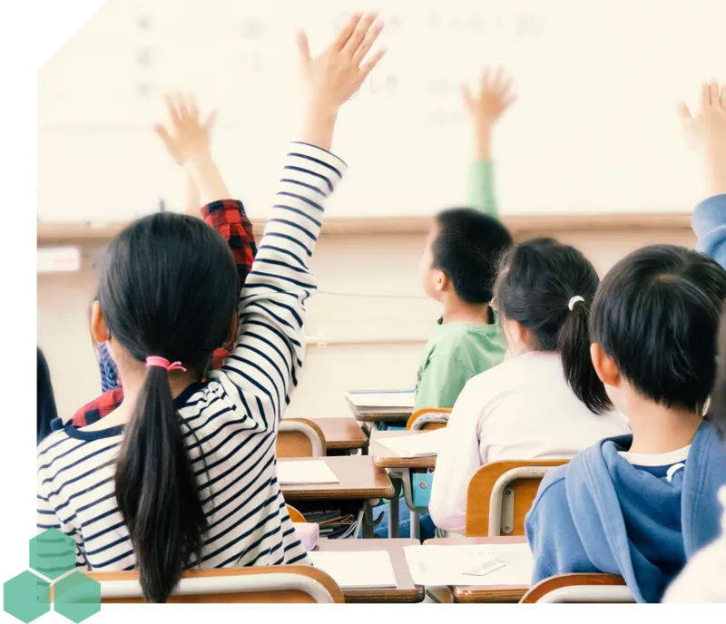 教室で手を挙げる子供たちの写真