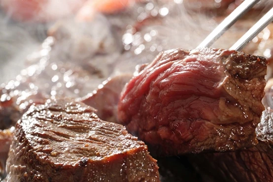 バーベキューの分厚い肉を焼く様子