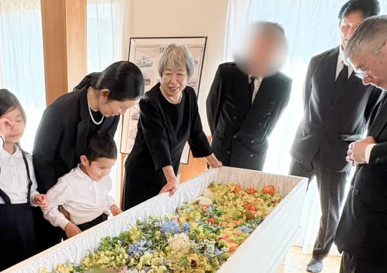色とりどりの花で埋め尽くされた棺を取り囲むご遺族の写真