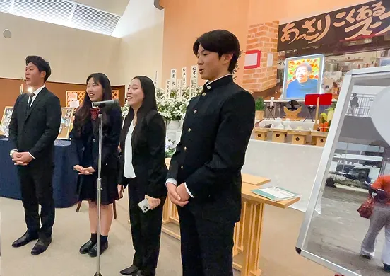 ラーメン屋を模したご葬儀会場で司会をするご遺族の写真
