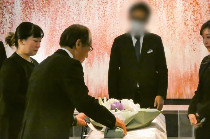 ラベンダーを添えた花束を棺の上に乗せる様子