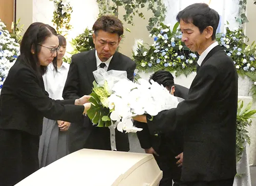 葬儀事例「父から学んだこと」のギャラリー画像3枚目 お棺の上に花束を置かれるご家族