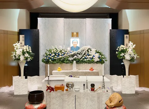 葬儀事例「靴職人の夫」のギャラリー画像2枚目 白い花が飾られた祭壇